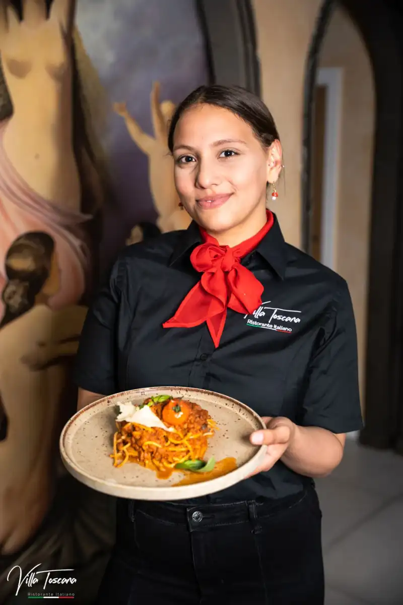 A member of the Villa Toscana team serving a plate of pasta