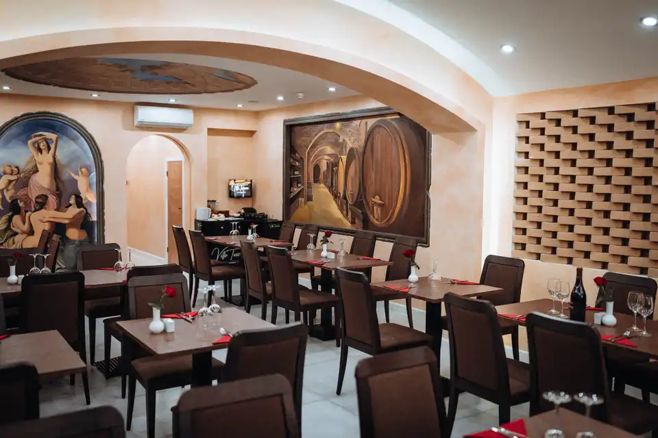 Set tables beneath cream arches and Italian murals at Villa Toscana