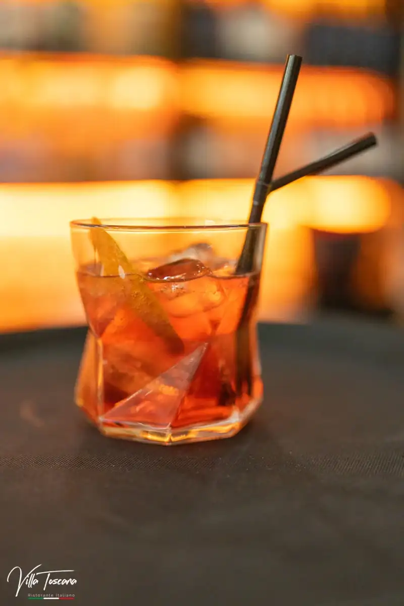 An amber aperitivo with a citrus slice at the restaurant bar