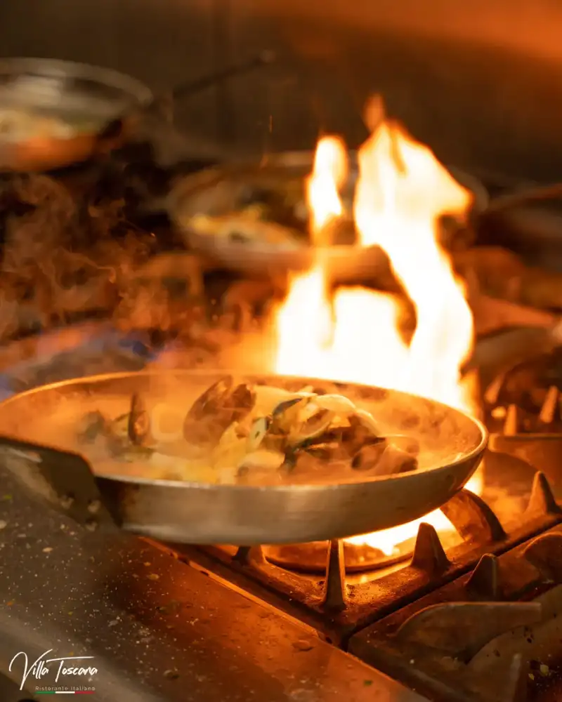 A pan of pasta over a flame in the Villa Toscana kitchen