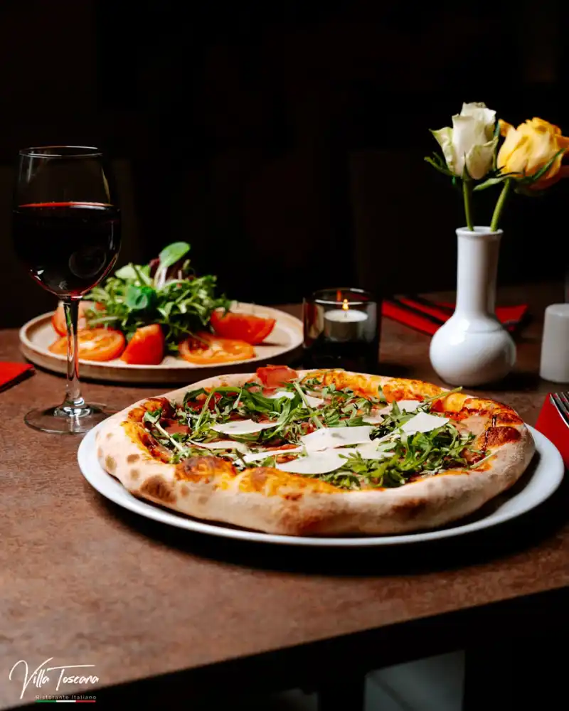 Freshly baked pizza at a table with a glass of red wine